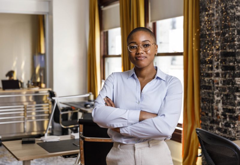 Confident female entrepreneur standing with arms crossed at office